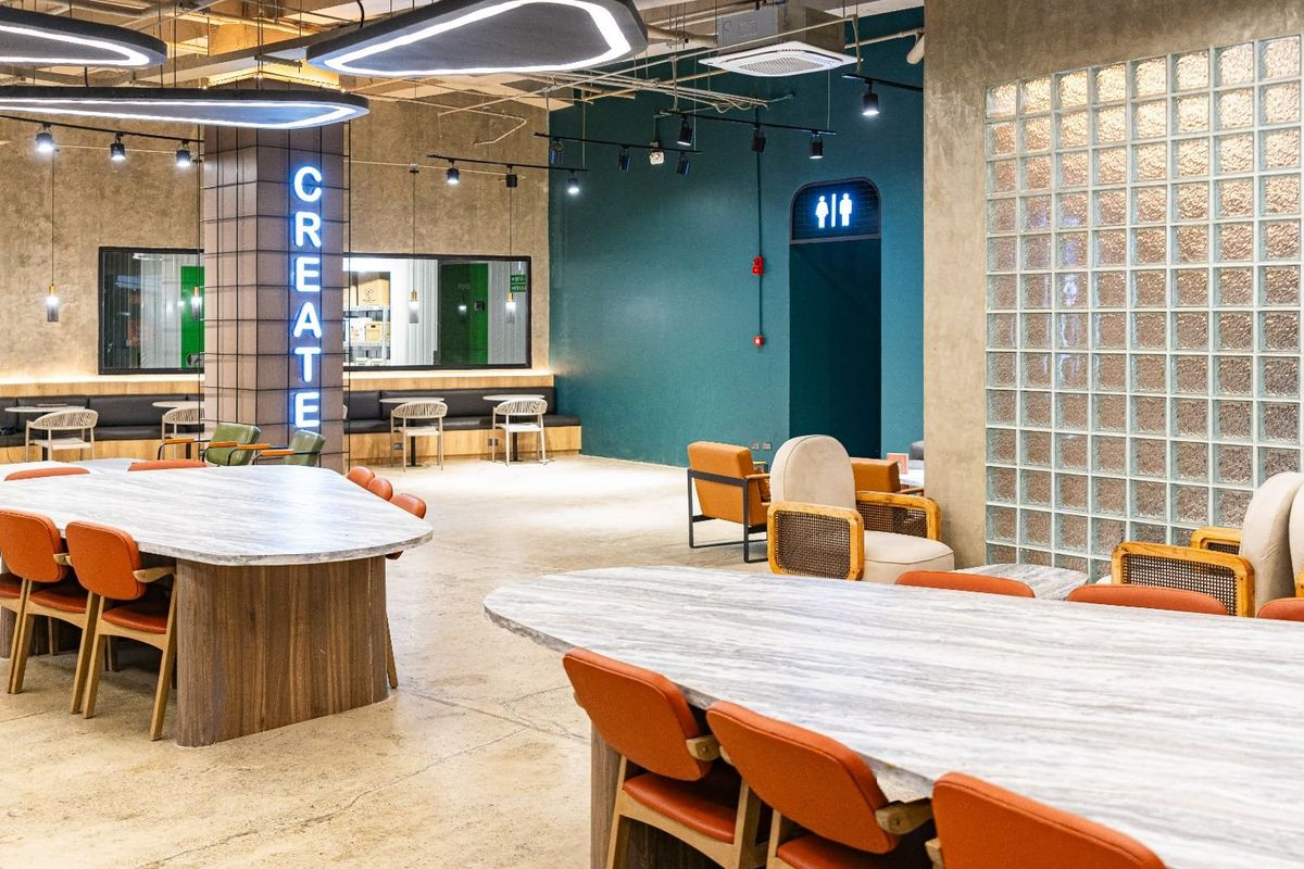 The Nest lounge with marble tables, orange chairs and a lit CREATE column