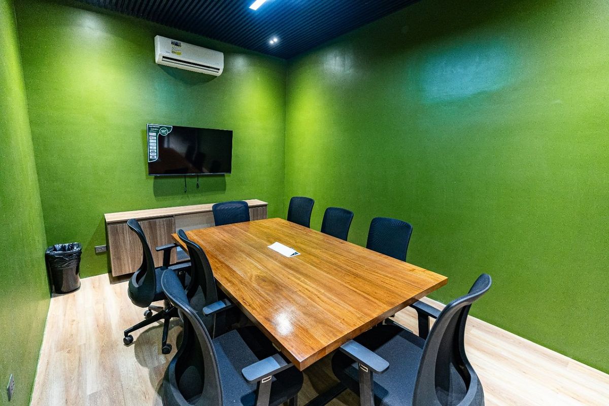 The small meeting room with green walls and a table for six
