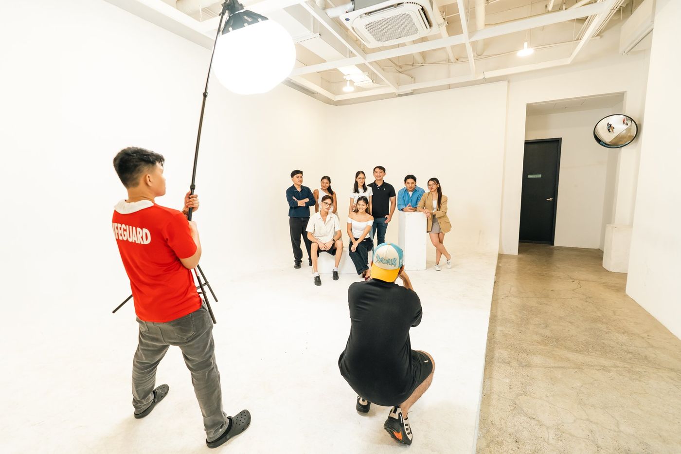 A photographer and lighting assistant shooting a group portrait on the cyclorama